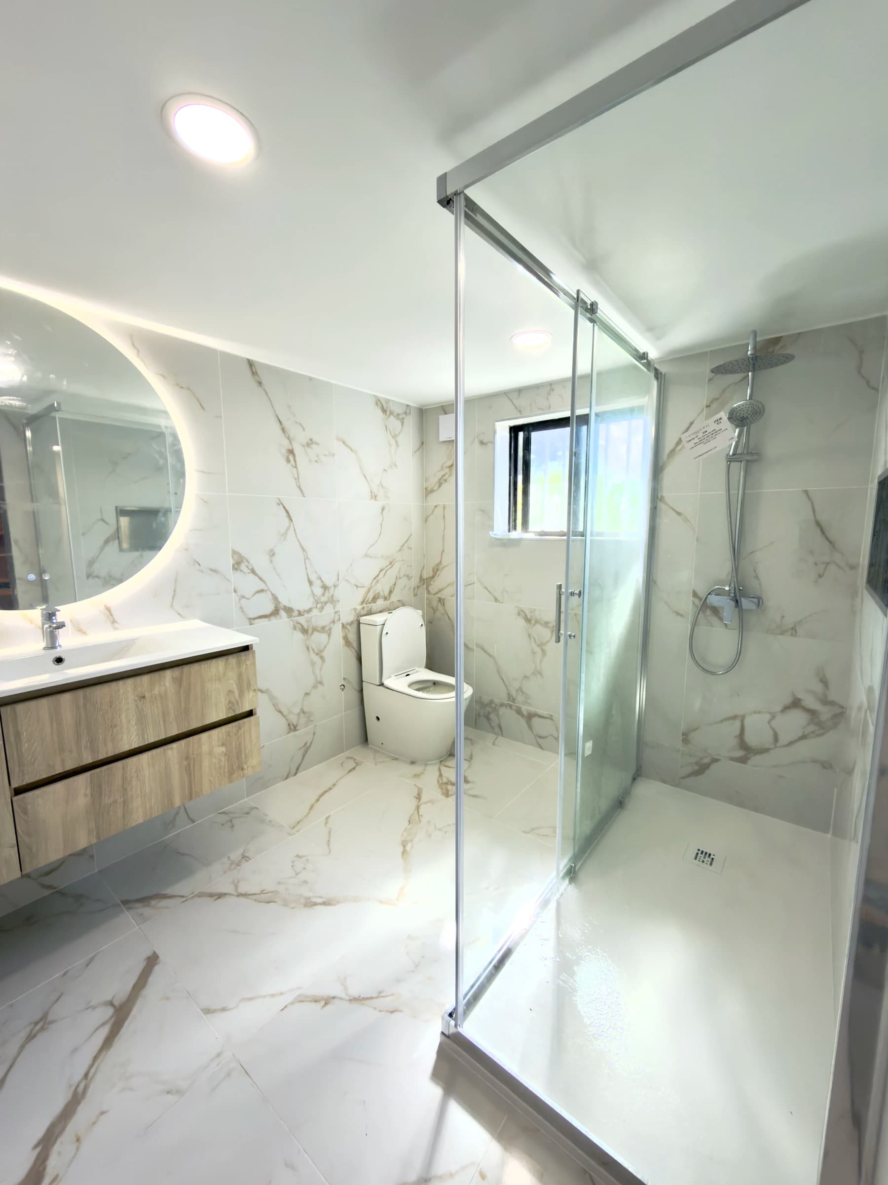 Casa de banho moderna em Estarreja, Aveiro, com revestimento cerâmico efeito mármore, duche walk-in e móvel suspenso em madeira natural — remodelação VPObras