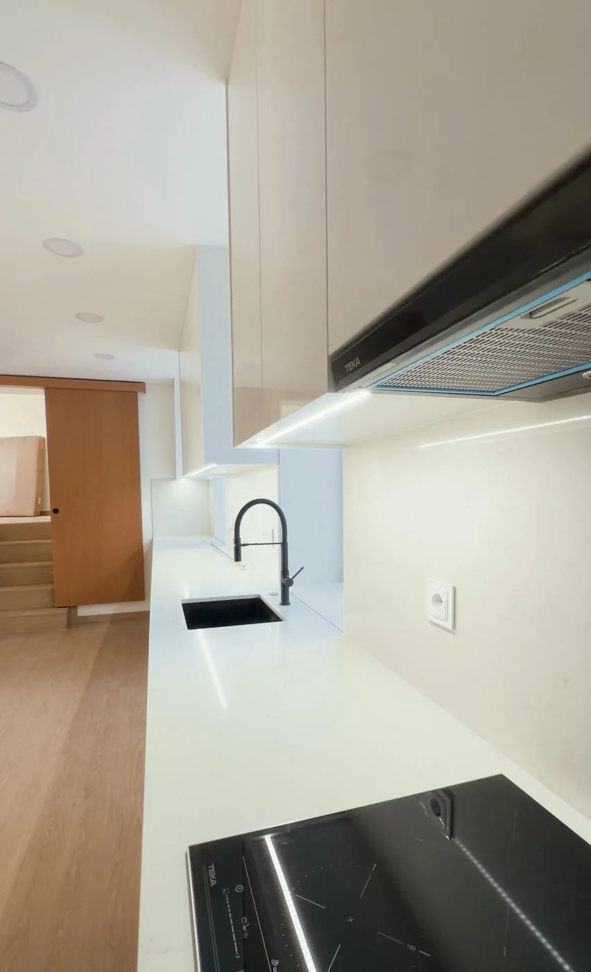 Detalhe da cozinha com mobiliário lacado branco e painel decorativo ripado em madeira, Estarreja Aveiro