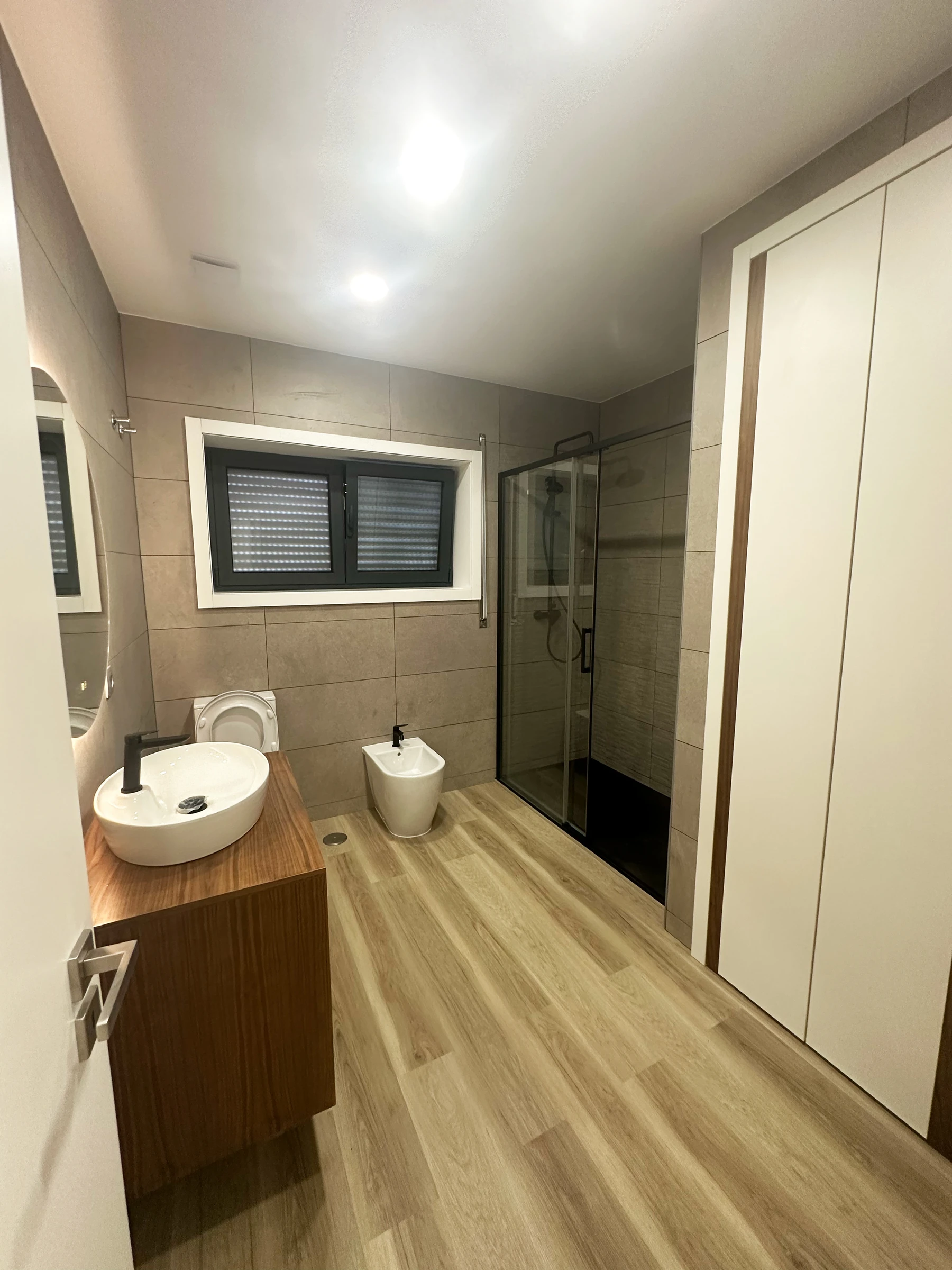 Detalhe da zona de lavatório com móvel em madeira natural, lavatório de pousar e torneira em preto mate, casa de banho Estarreja Aveiro