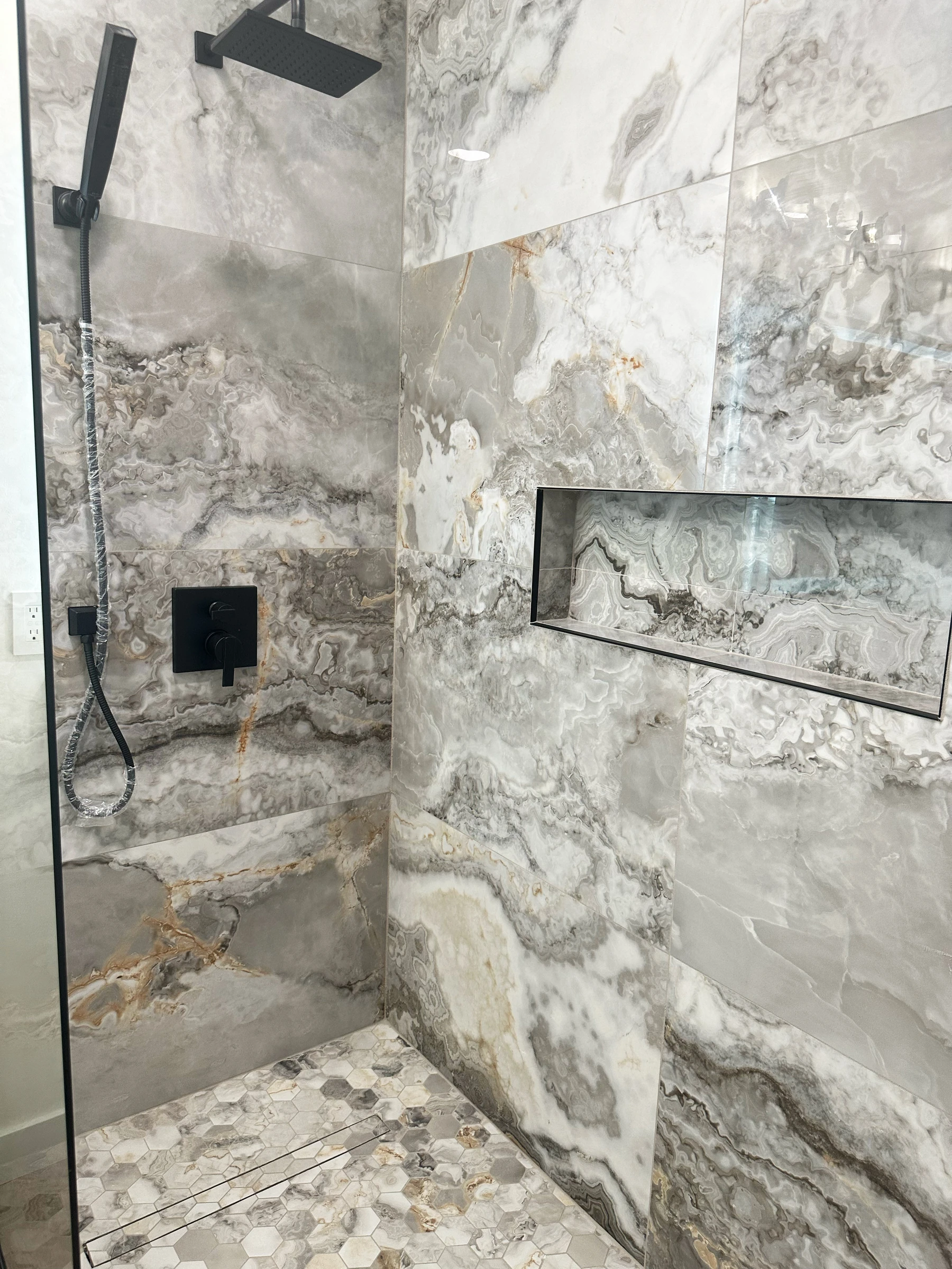 Perspetiva do duche walk-in com vidro temperado, nichos embutidos e base em pedra natural rolada, casa de banho Maple Grove, Minnesota